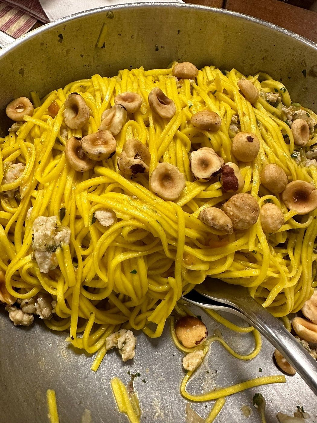 Tajarin all’uovo con nocciole intere in una padella di alluminio